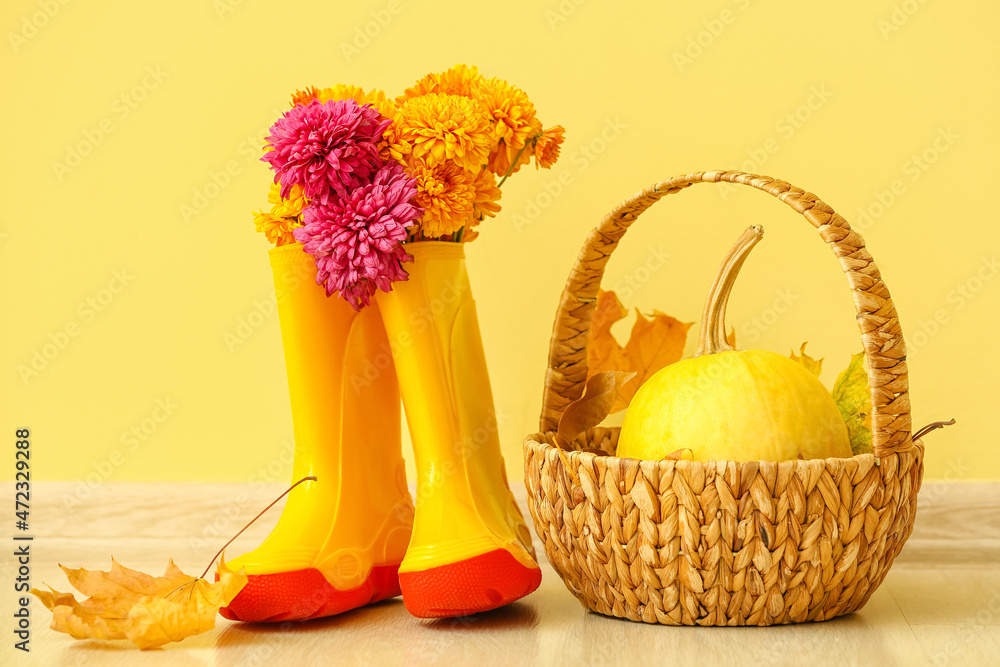 一双橡胶靴、鲜花和篮子，南瓜靠在彩色墙上
