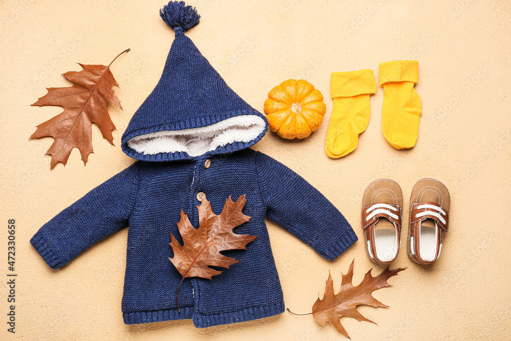 时尚的婴儿服装、鞋子、南瓜和秋叶以彩色为背景