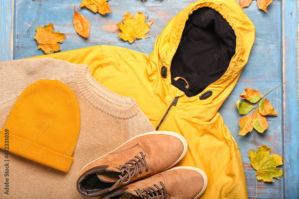 时尚的夹克、毛衣、帽子、鞋子和彩色木质背景的秋叶