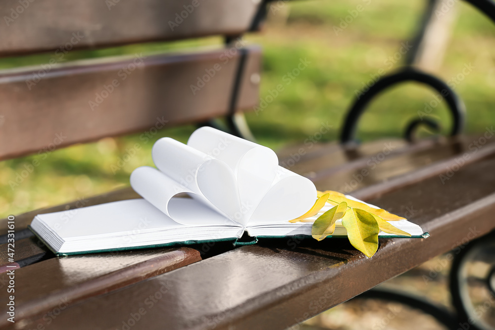 公园木凳上折页的书和秋叶的树枝