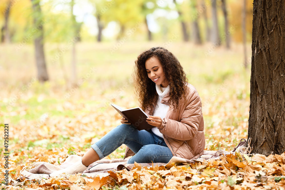 年轻的非裔美国女性在秋季公园看书