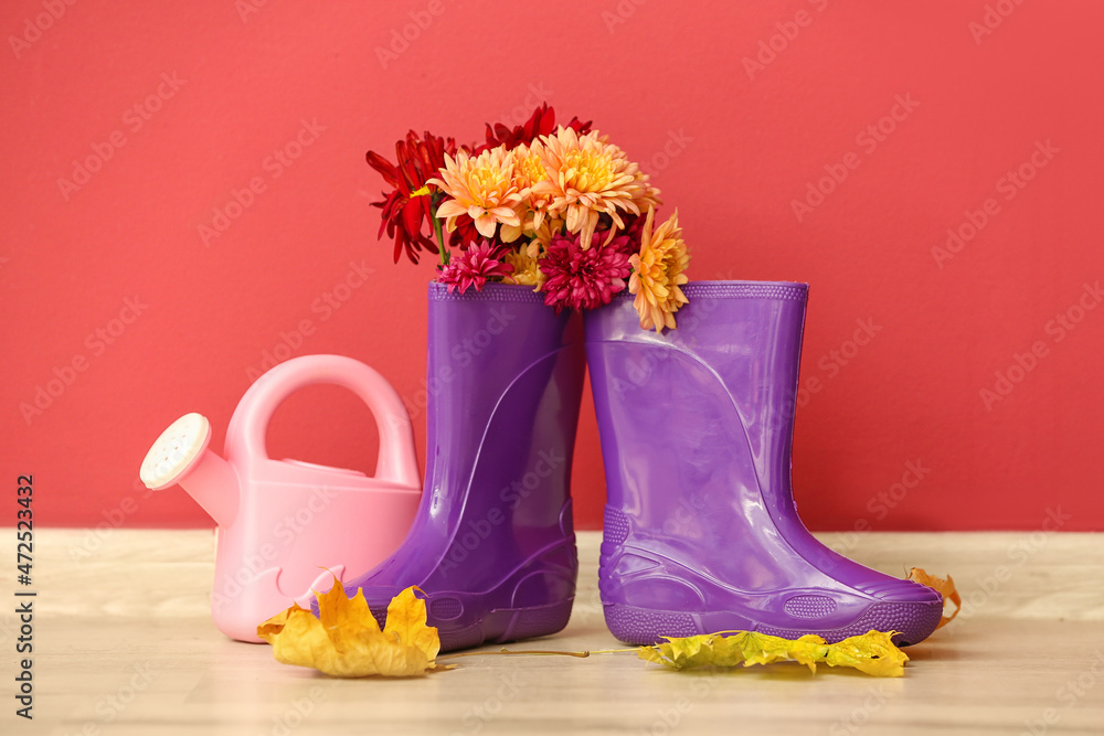 橡胶靴、喷壶和彩色墙上的地板上的花朵