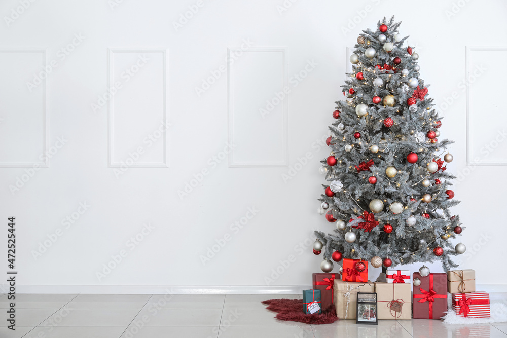 白墙附近美丽的圣诞树和礼盒