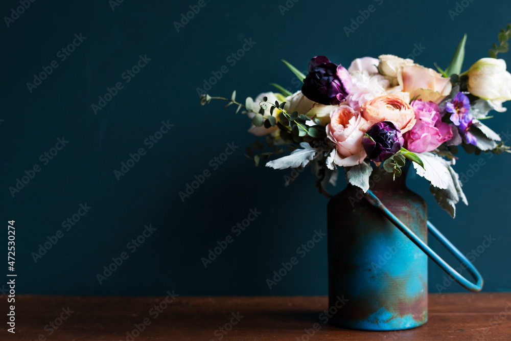 木桌上金属花瓶中的各种鲜花
