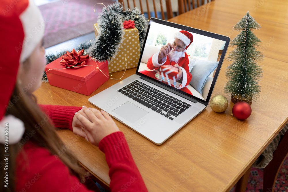 戴着圣诞帽的白人妇女与穿着圣诞老人服装的老年男子进行笔记本电脑圣诞视频通话