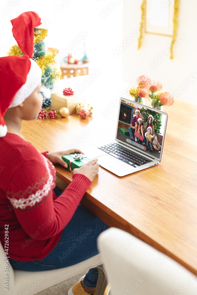 戴着圣诞老人帽的非裔美国妇女与微笑的家人进行圣诞笔记本电脑视频通话