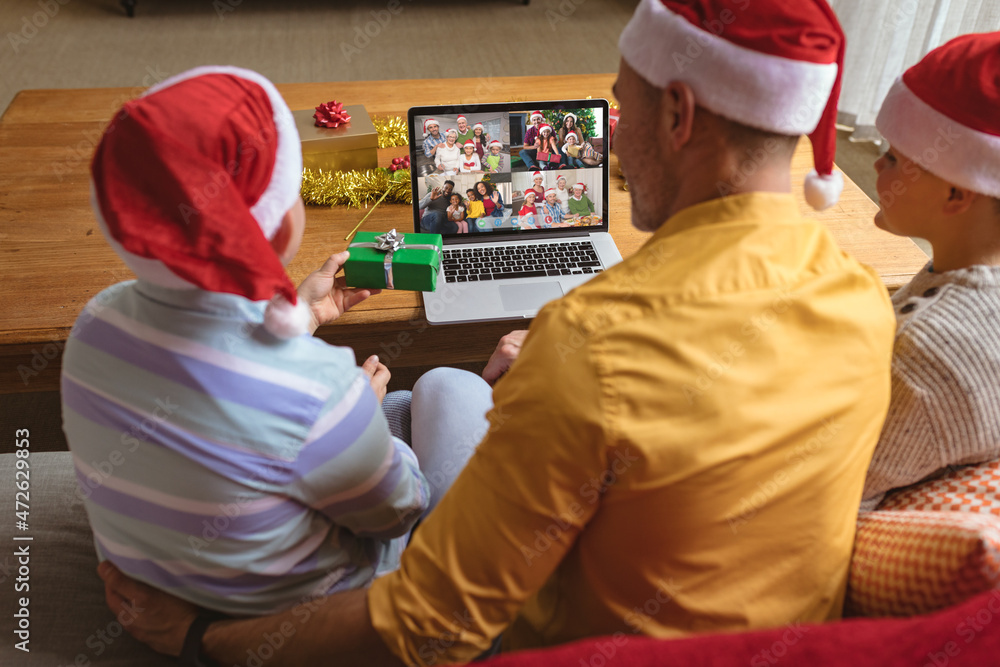 戴着圣诞老人帽的白人父子与四个家庭进行笔记本电脑圣诞集体视频通话