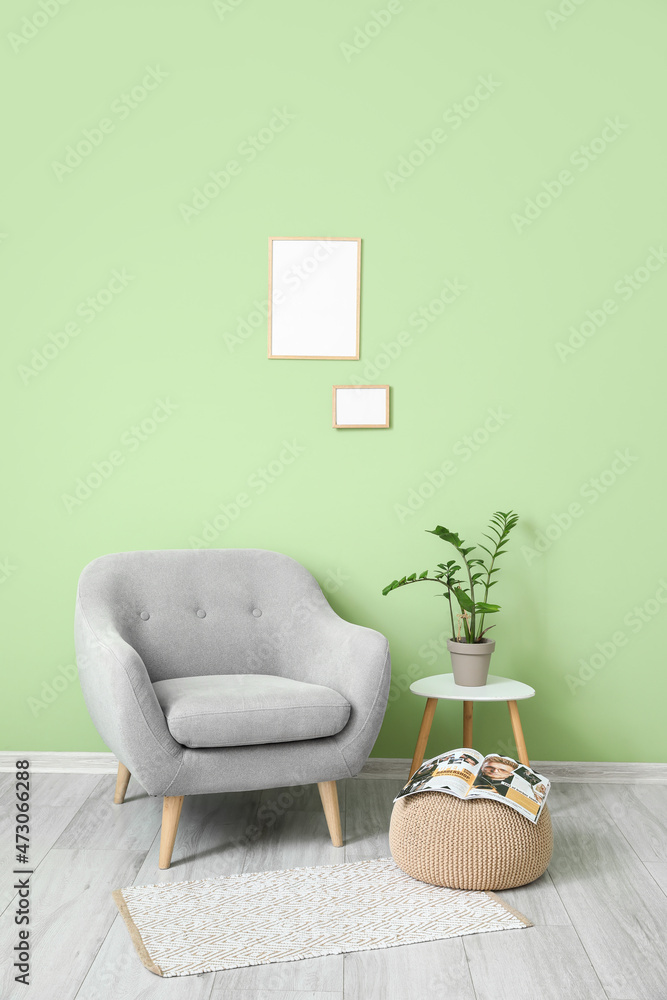 绿色墙上挂着灰色扶手椅、沙发、桌子和空白框架