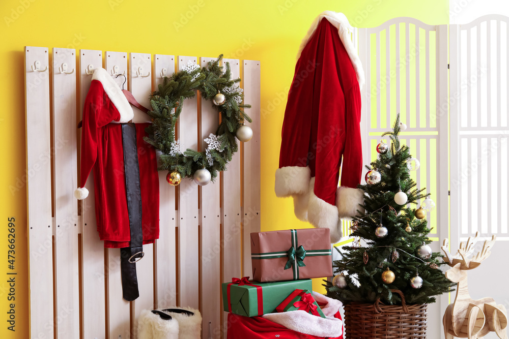 走廊里挂着圣诞老人服装的衣架、装着礼盒的袋子和圣诞树