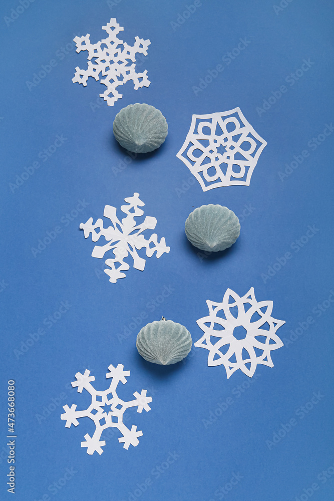 蓝色背景下美丽的纸雪花和圣诞球