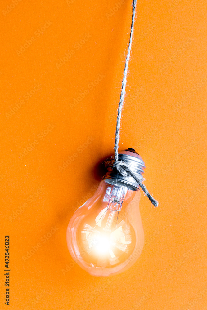 橙色背景下发光的灯泡