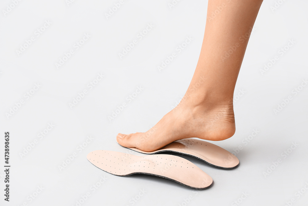 浅色背景下的女性足部和矫形鞋垫