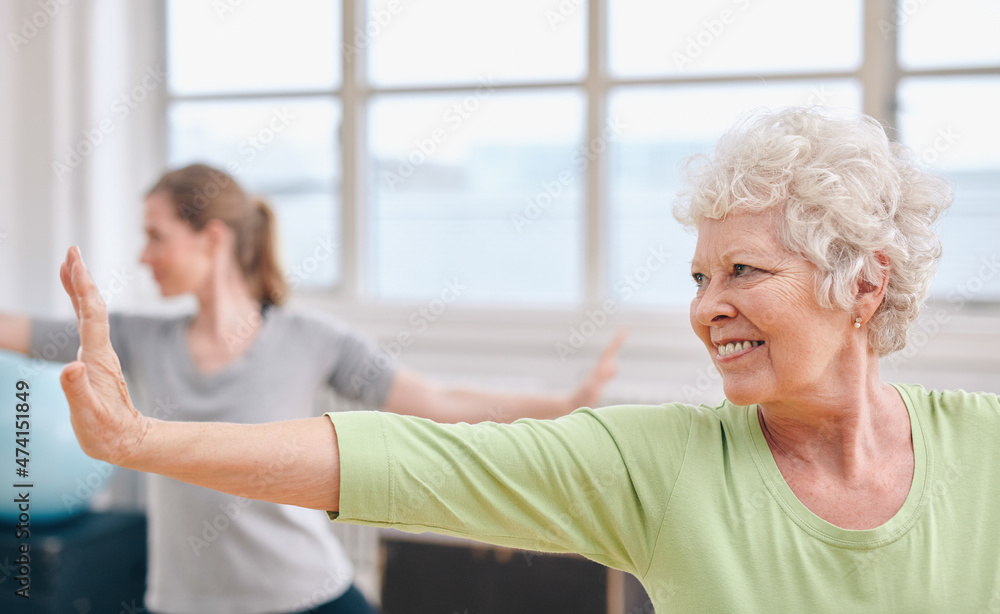 快乐的高年级女性在体育课上练习瑜伽。