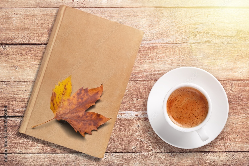 落叶背景下，木面上的一杯茶和一本书，秋天的季节