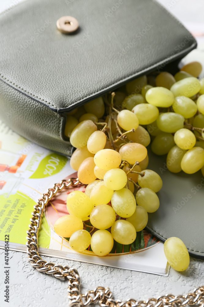 时尚的袋子，有成熟的葡萄和浅色背景的杂志，特写