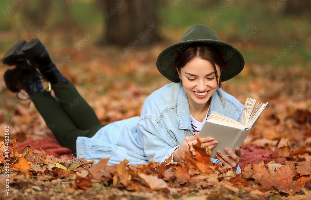 秋天公园里躺在格子布上看书的微笑女人