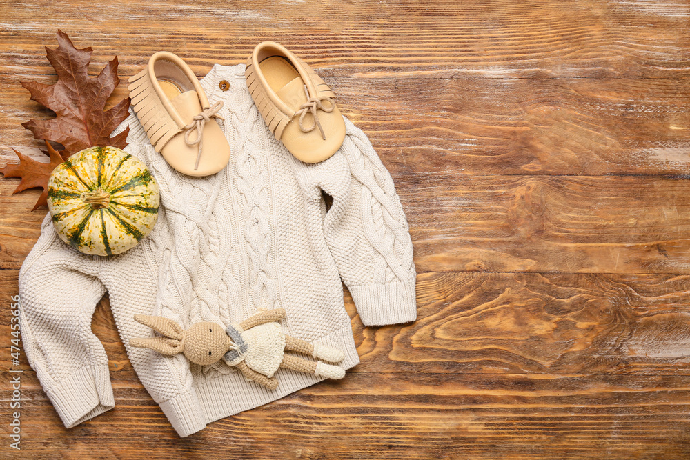 时尚的婴儿毛衣、玩具、鞋子和木背景南瓜