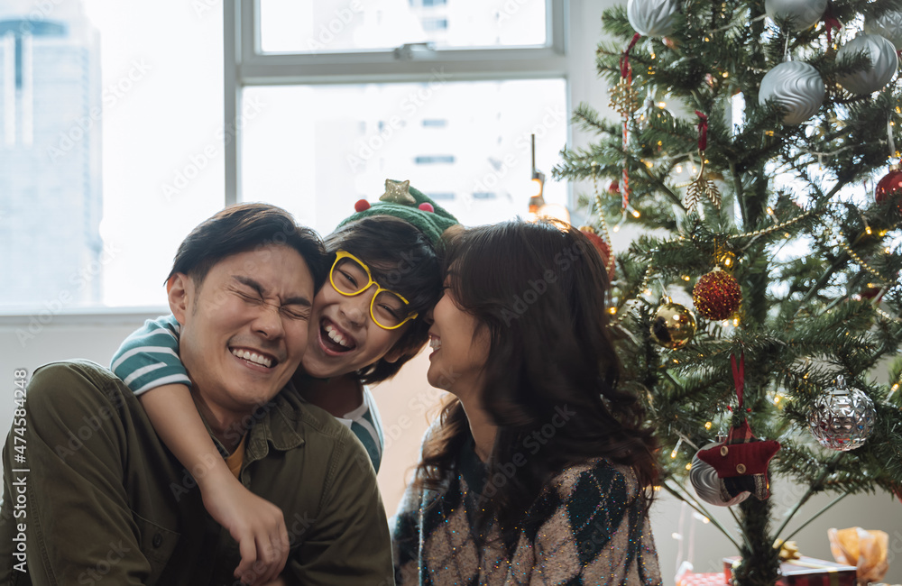 在家里的圣诞树旁描绘幸福的亚洲家庭。家庭、圣诞节和人们的聚会