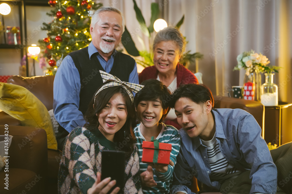 亚洲家庭在家里一起在圣诞树附近自拍。家庭、假期、圣诞节概念