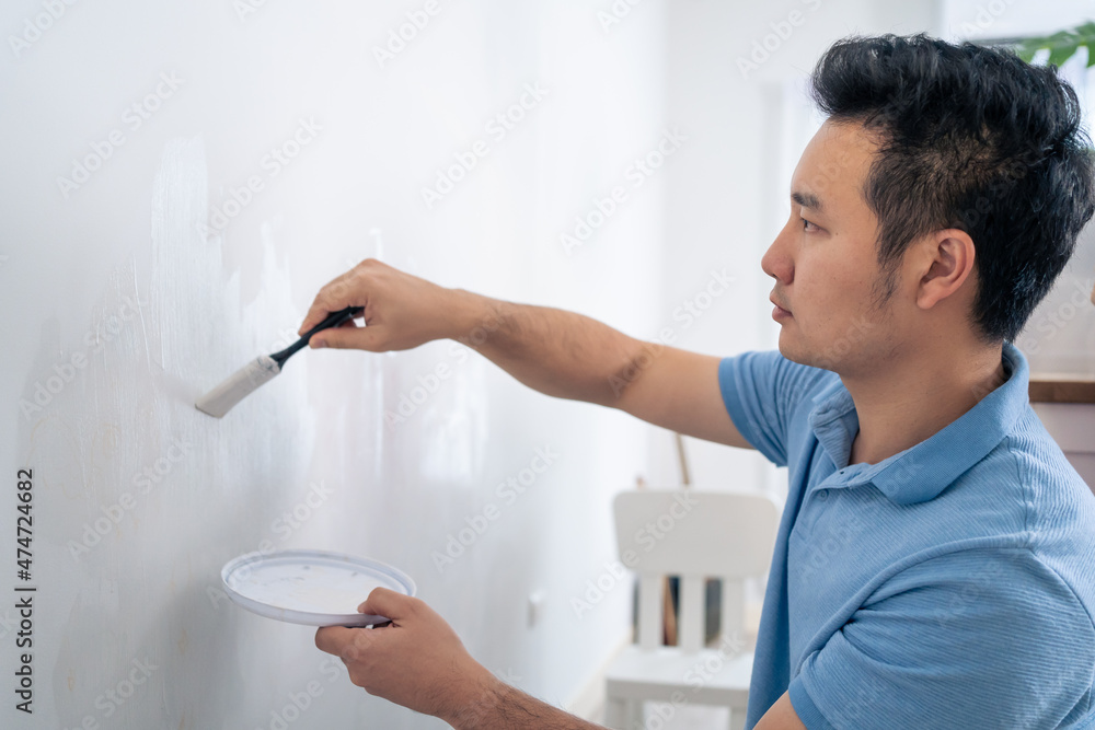 亚洲美女用刷子刷白墙修复客厅
