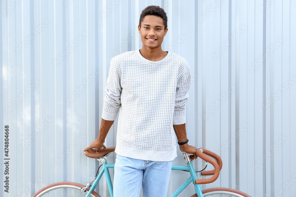 非洲裔美国少年骑自行车靠近蓝色围栏
