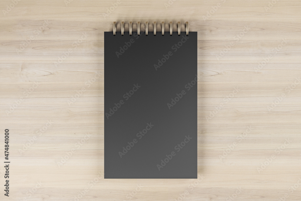 木制桌面背景上黑色弹簧记事本的俯视图和特写。适合您的实物模型