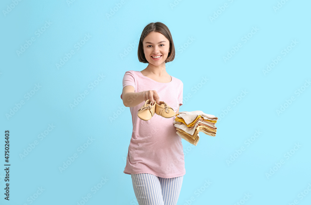 穿着婴儿鞋和蓝色背景衣服的年轻孕妇