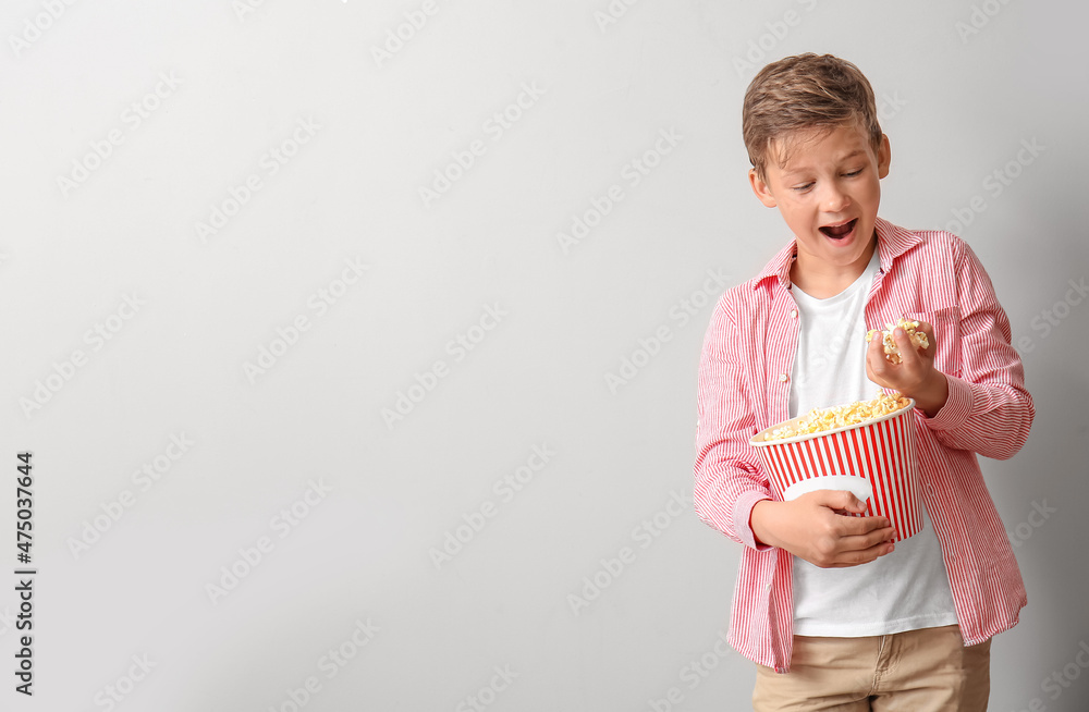 快乐的小男孩，浅色背景下有一桶美味的爆米花