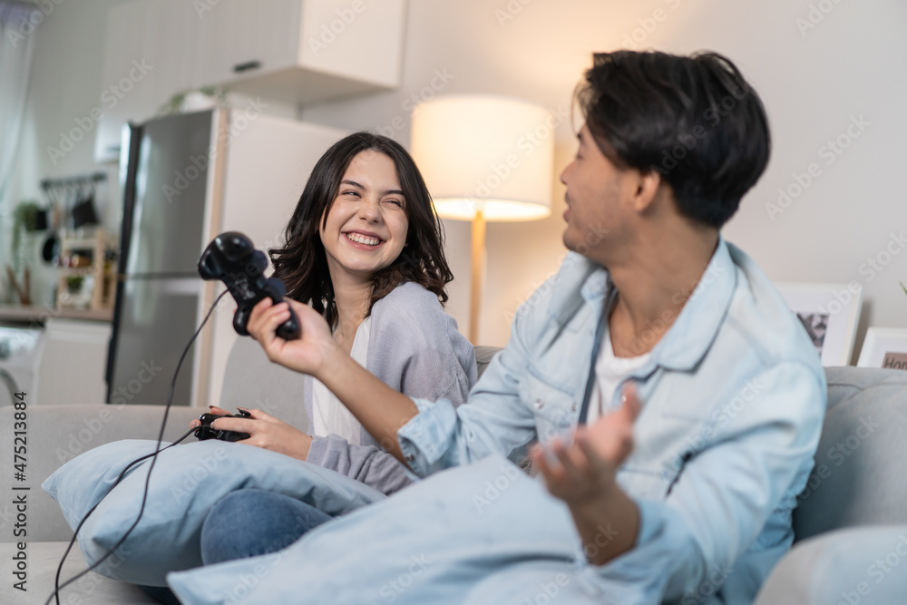 Asian young man and woman couple enjoy playing game together in house. 