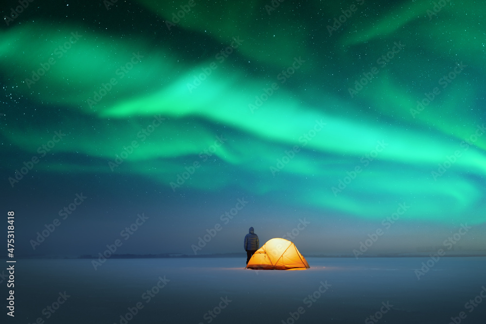 游客在黄色帐篷附近，在令人难以置信的星空背景下，从里面照亮