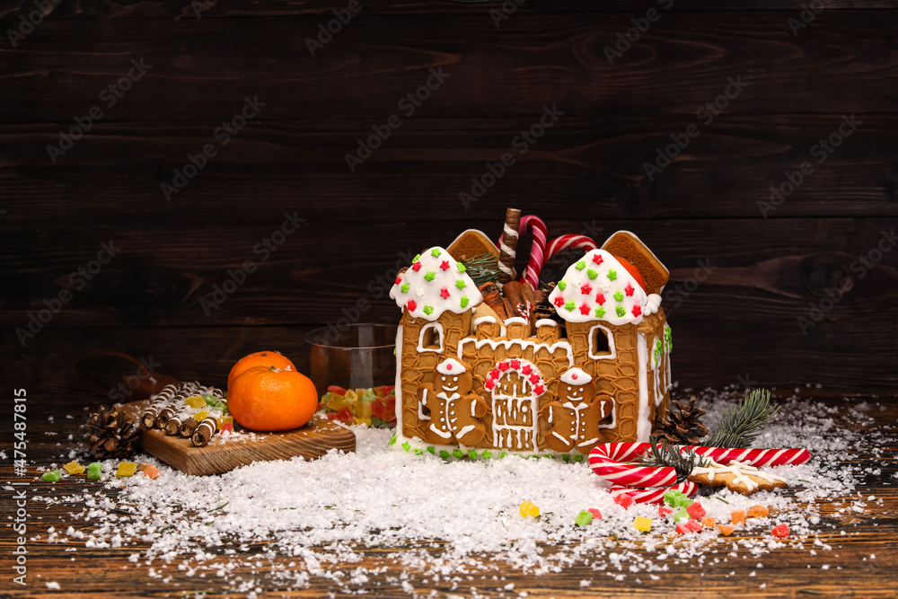 美丽的姜饼屋，木制背景上的橘子和雪