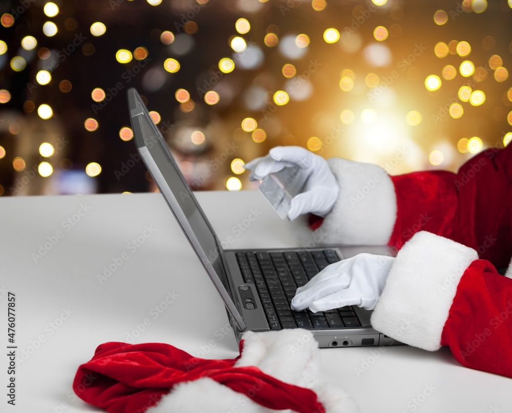 Female hands on the laptop with gifts and blurred bokeh lights. Christmas shopping online, sales and