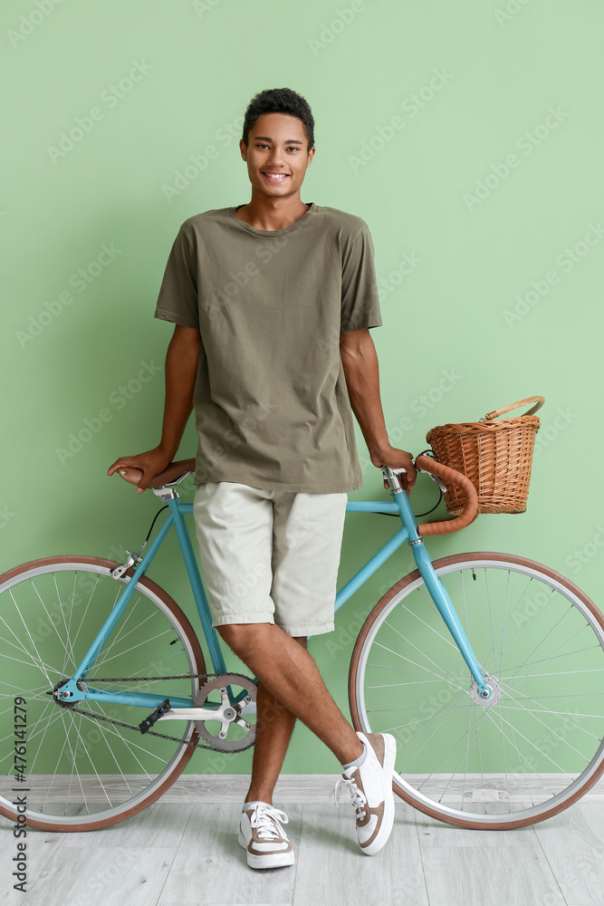 非洲裔美国少年骑自行车靠近绿墙