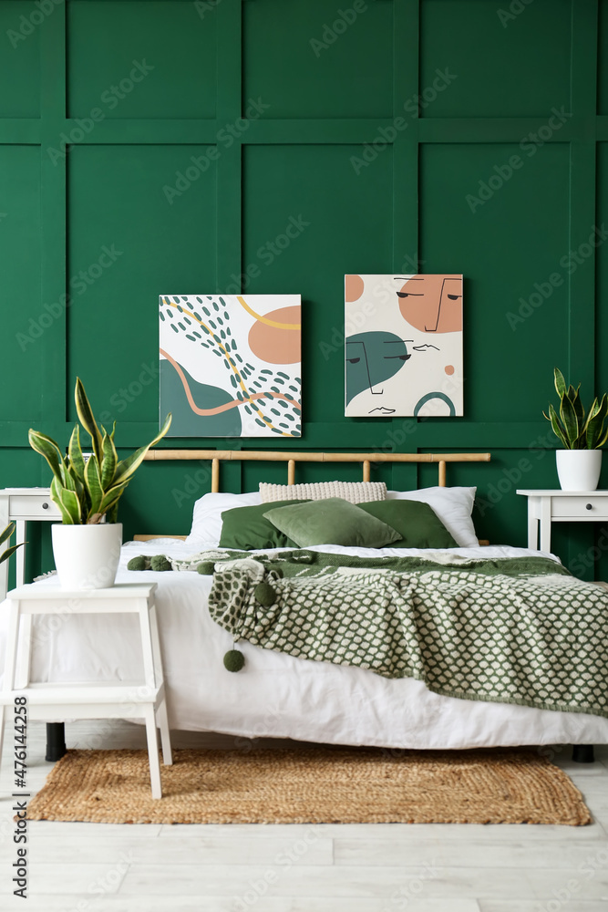 带绘画、室内植物和绿色墙壁的时尚卧室内部
