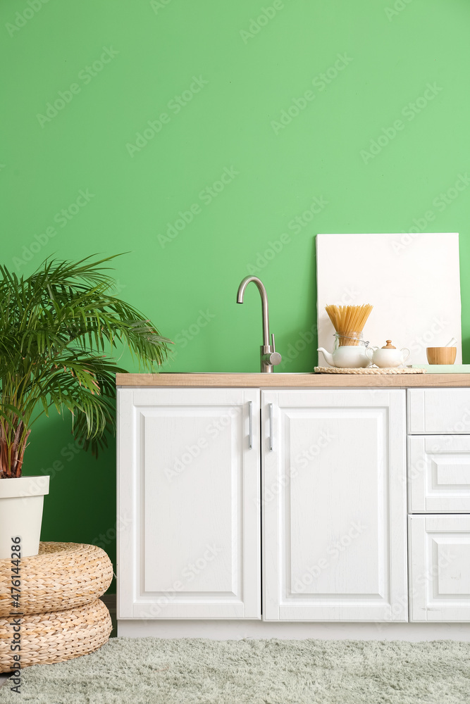 时尚厨房内部，配有白色柜台、水槽、框架和绿色墙壁
