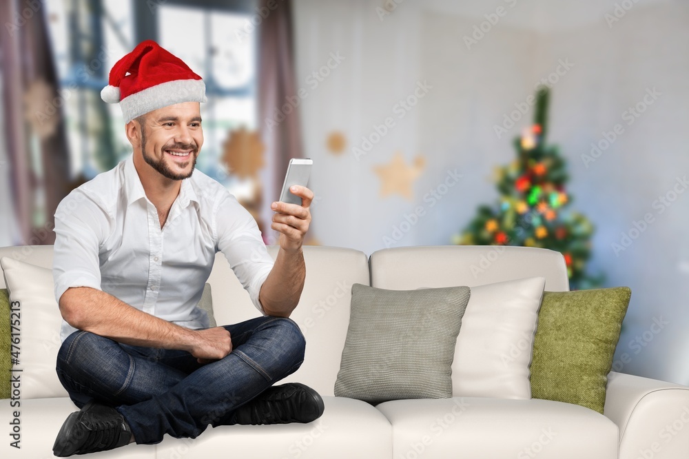 圣诞夜，年轻快乐的男人在家里用智能手机打视频电话。