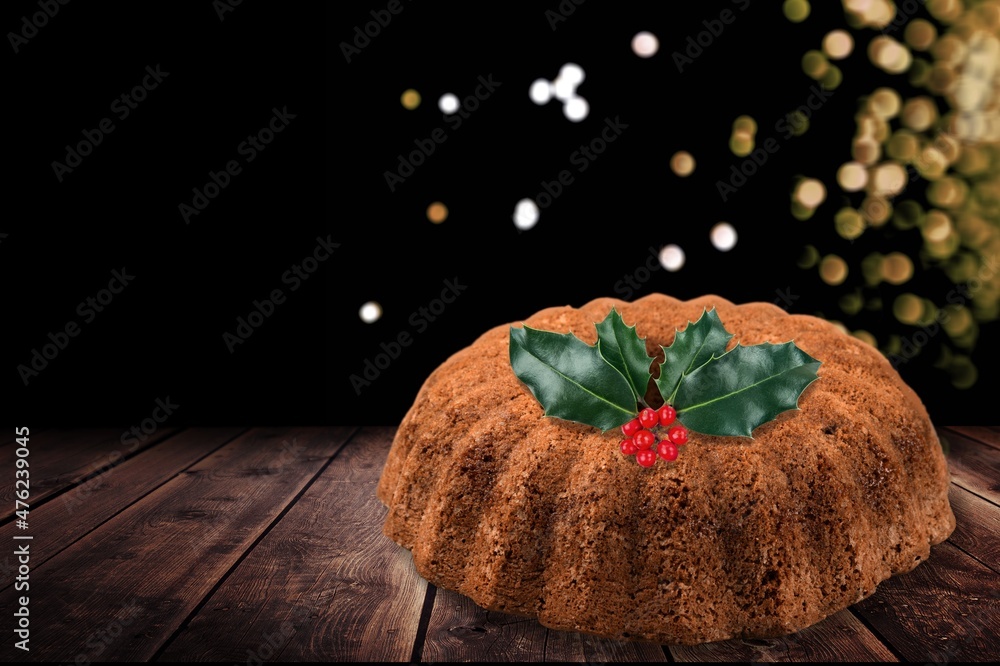 圣诞布丁，水果蛋糕。传统节日甜点。深色背景，带灯花环。