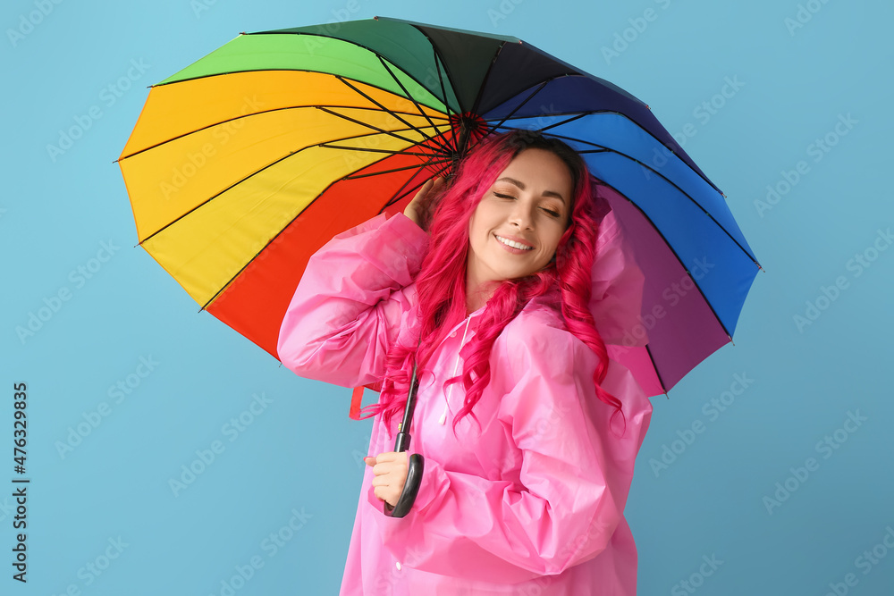 美丽的女人穿着雨衣，颜色背景上带着雨伞