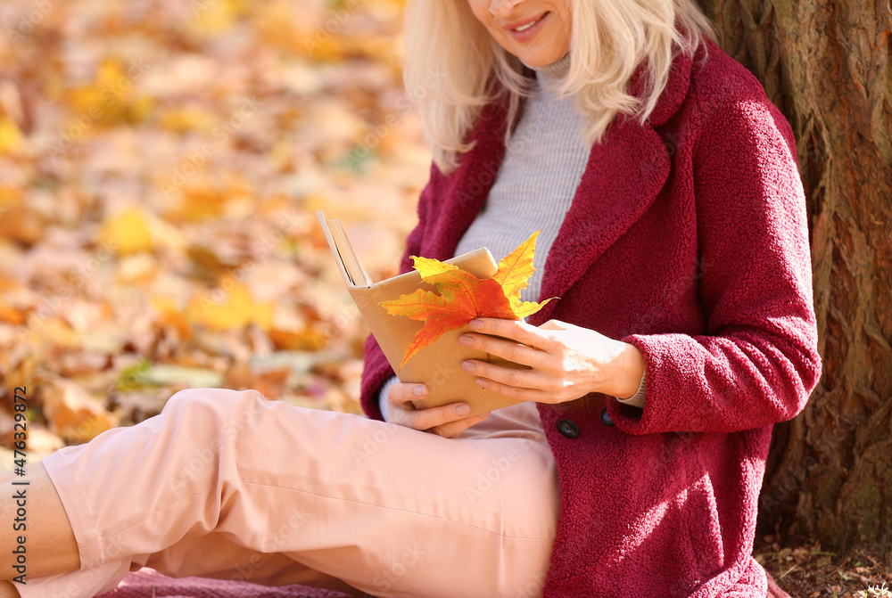 秋天公园里的成熟女人读书