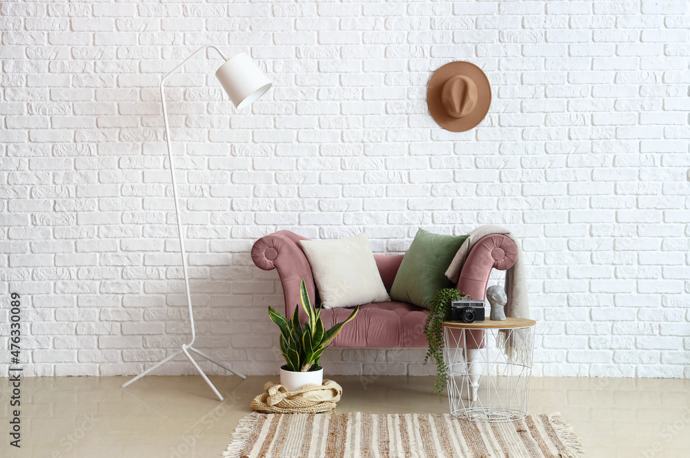 房间白色砖墙附近有室内植物和灯的时尚舒适扶手椅