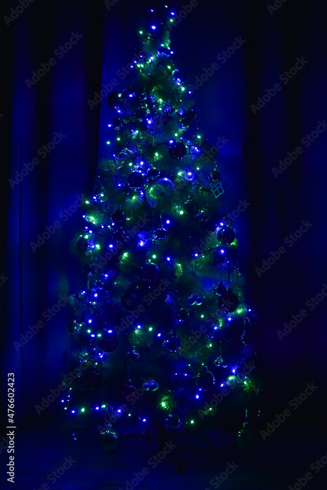 在黑暗中装饰圣诞树，发出绿光和蓝光