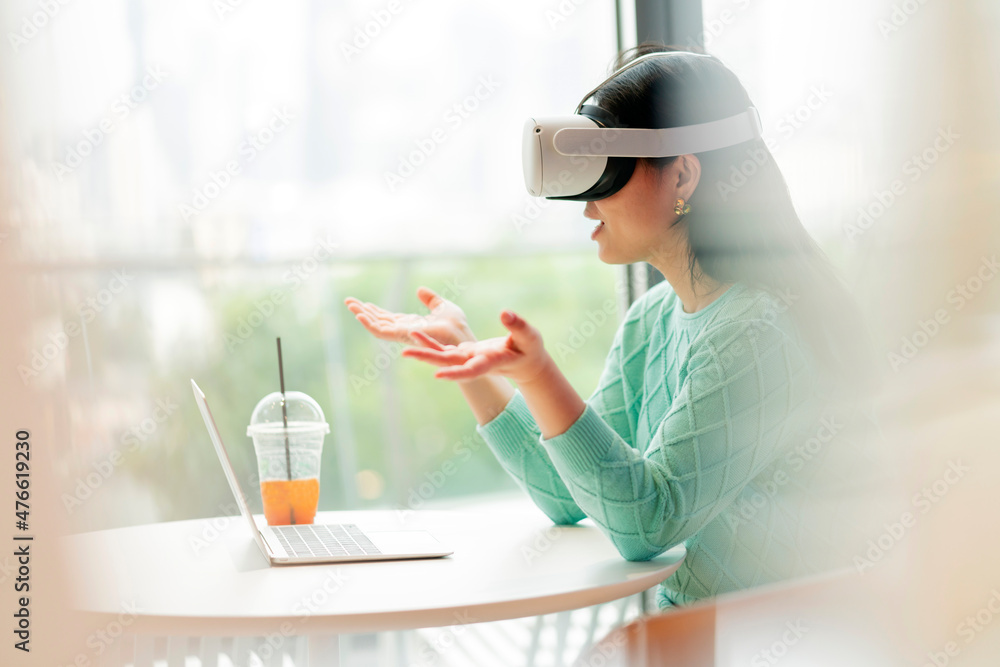 聪明迷人的亚洲女企业主戴着虚拟现实眼镜，享受休闲元宇宙
