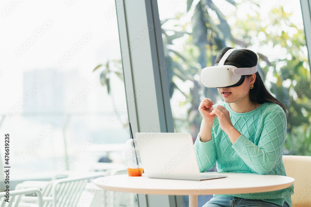 聪明迷人的亚洲女企业主戴着虚拟现实眼镜，享受休闲的元宇宙