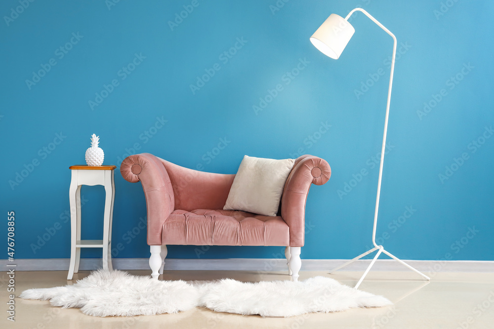 时尚舒适的扶手椅，靠近房间的蓝色墙壁，配有桌子和台灯