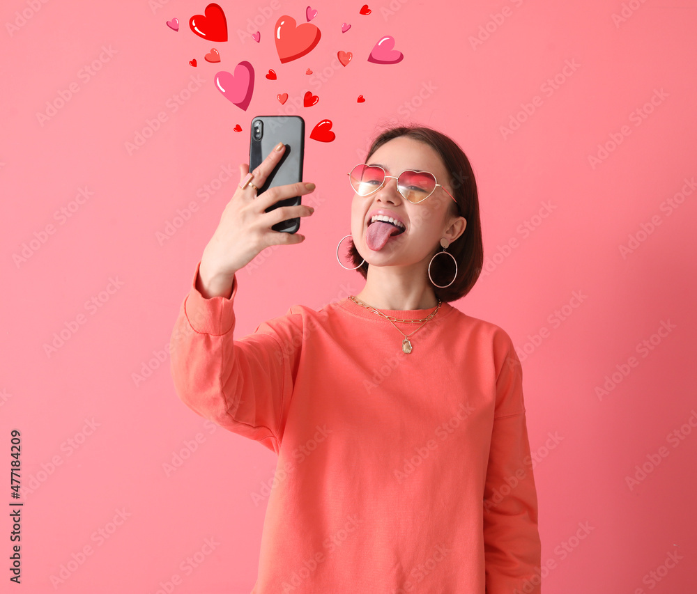 美丽的年轻女子，手机在粉色背景下发送爱情信息