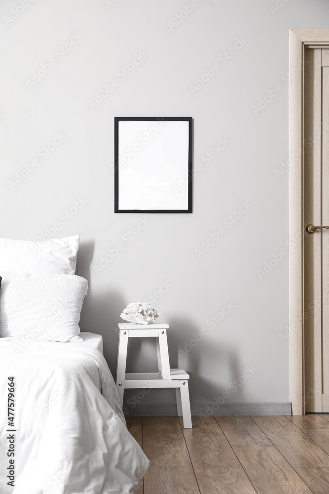白色台阶凳，带装饰，靠近浅色墙壁的床