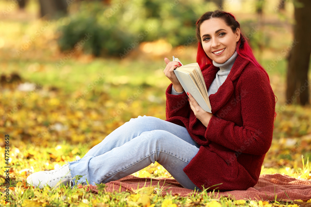 Beautiful woman with warm coat and book in autumn park
