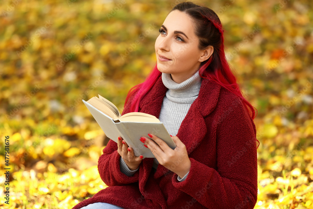 秋天公园里穿着保暖外套、看书的梦中美女