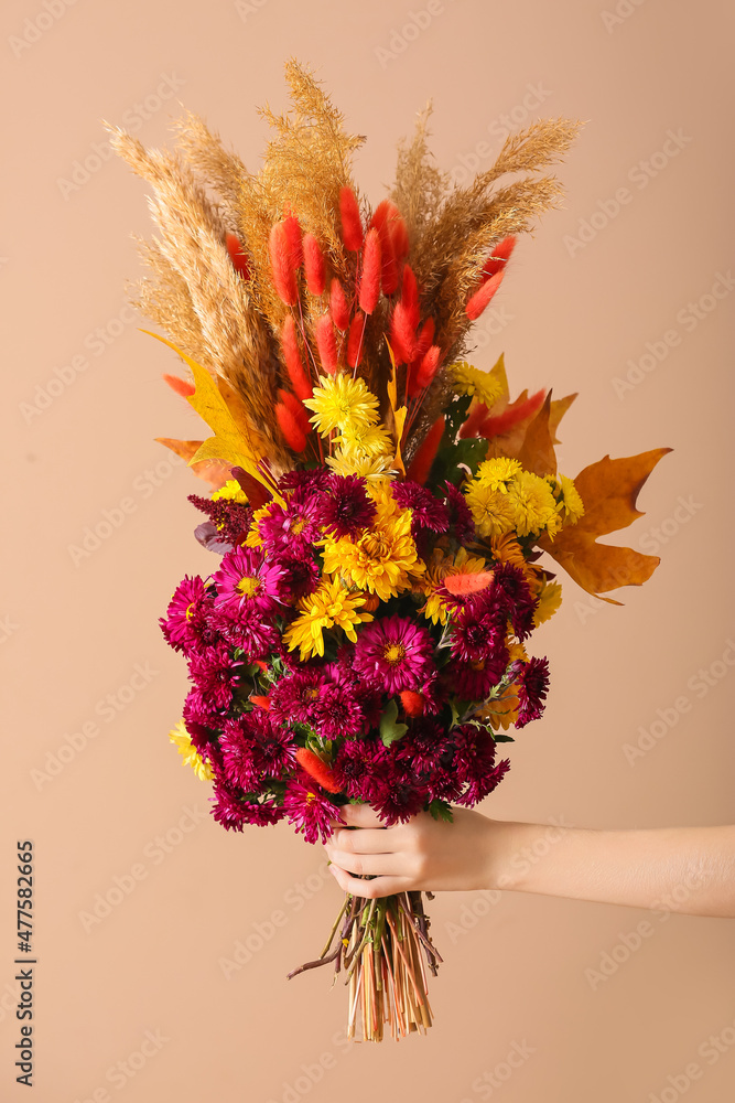 女性手，彩色背景上有美丽的秋天花束，特写