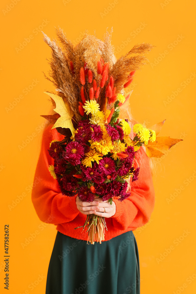 女人用美丽的秋色花束遮住脸